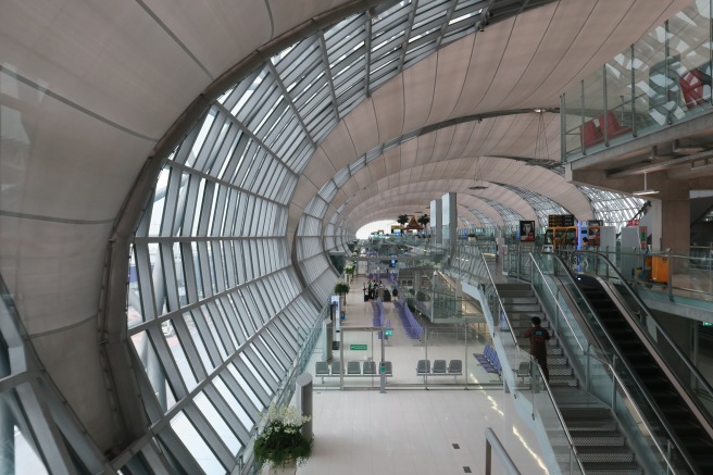 a large glass ceiling with people walking and escalators