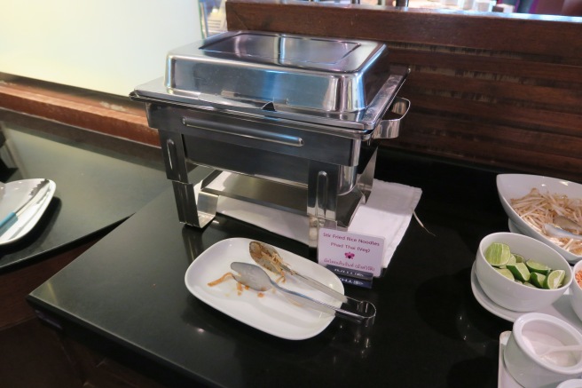 a silver tray with spoons and a plate on a black surface