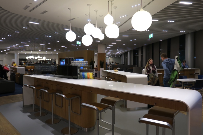 a group of people standing in a room with a counter and stools