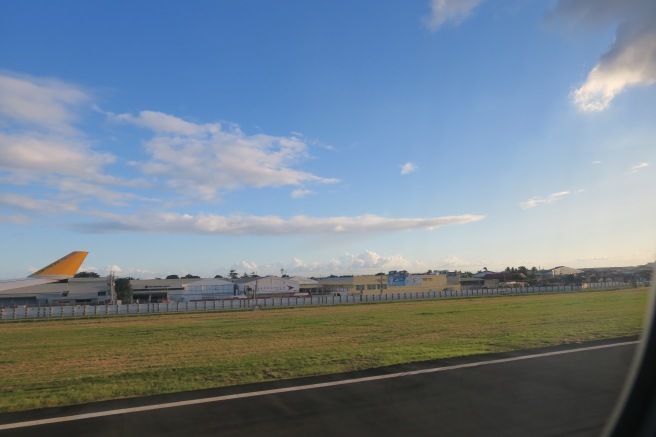 a road with grass and buildings in the background