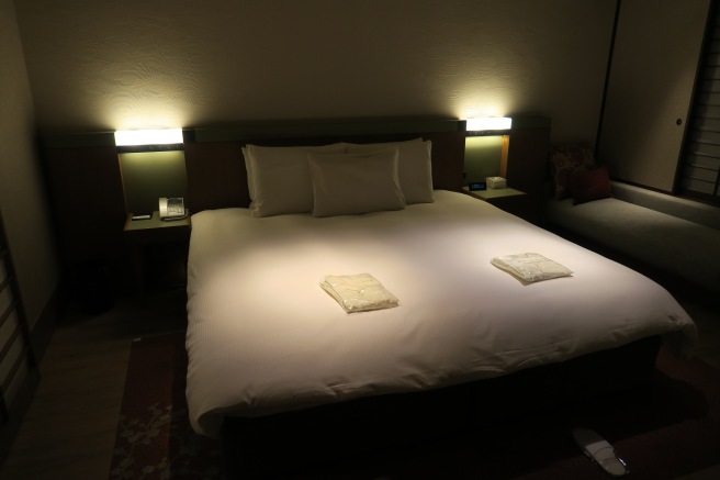 a bed with white sheets and pillows