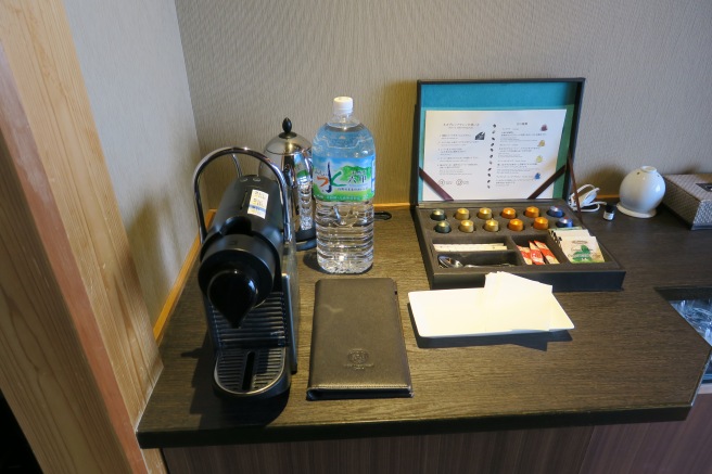 a table with a coffee machine and a wallet and a bottle of water