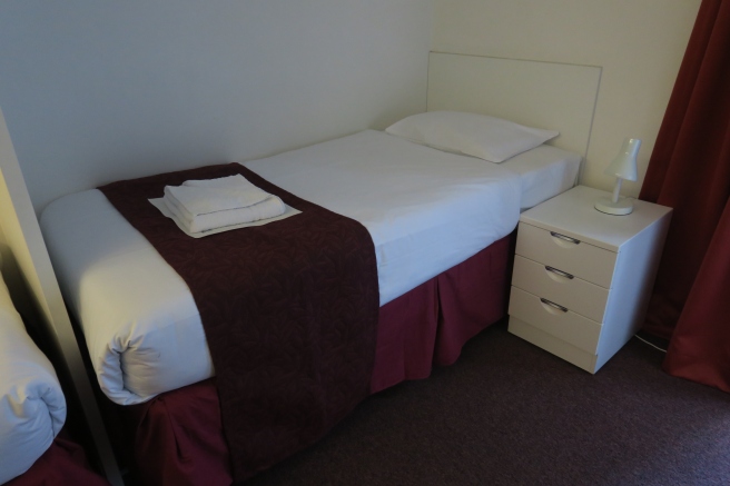 a bed with a red blanket and white pillows