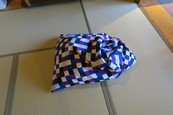 a purple and white checkered pillow on a white mat