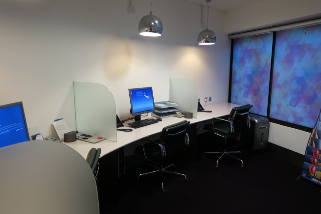 a desk with a computer and chairs