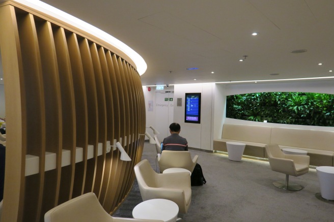 a man sitting in a room with white chairs and a screen