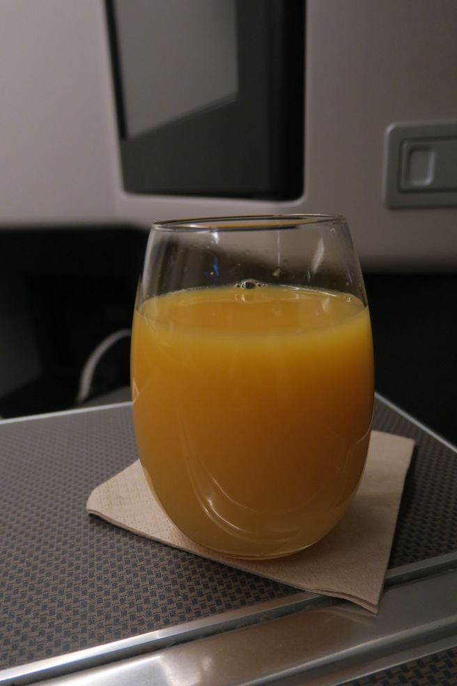 a glass of orange juice on a napkin