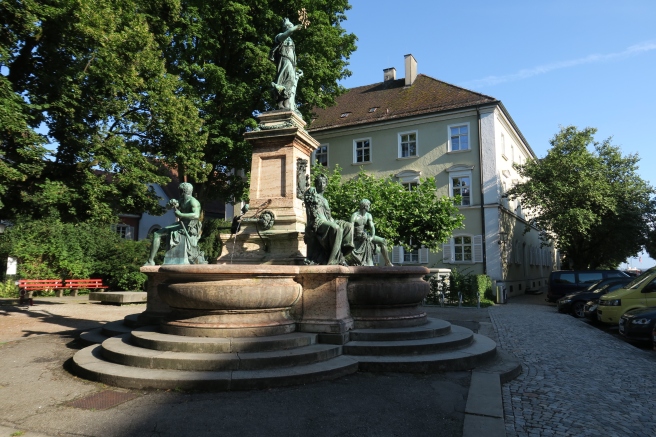 a statue of a woman sitting on a pedestal in front of a building