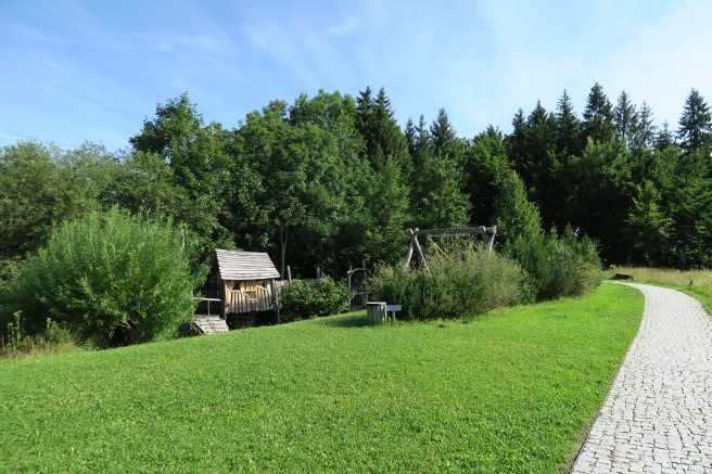 a green lawn with trees and a wooden structure