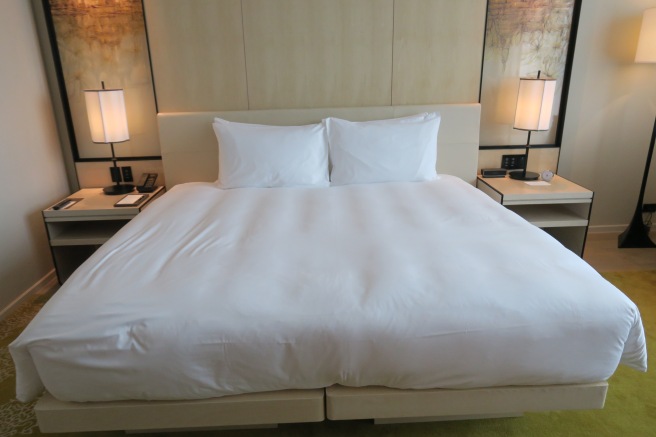 a bed with white sheets and lamps