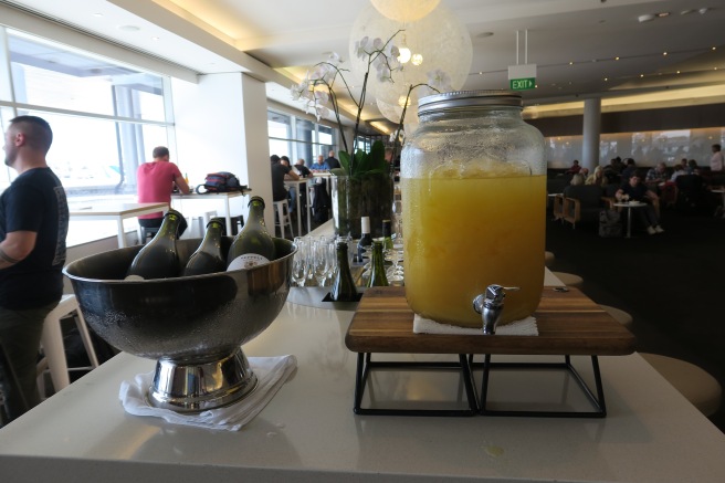 a glass jar with a drink dispenser next to a bowl of wine bottles