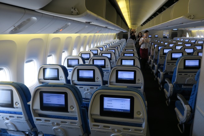 a row of seats with monitors on the side of the plane