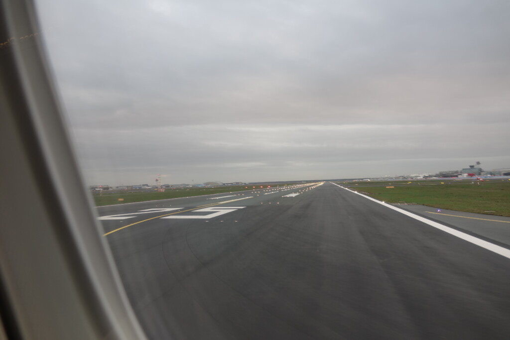 a runway with grass and buildings in the background