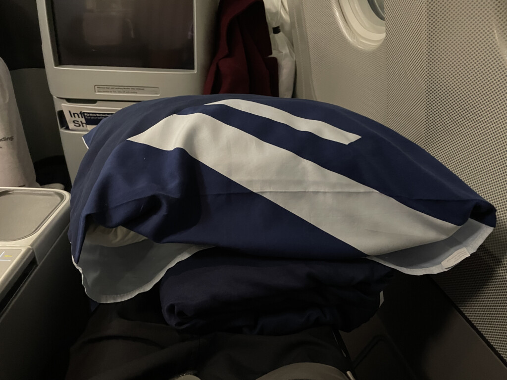 a blue and white pillow on a stack of clothes