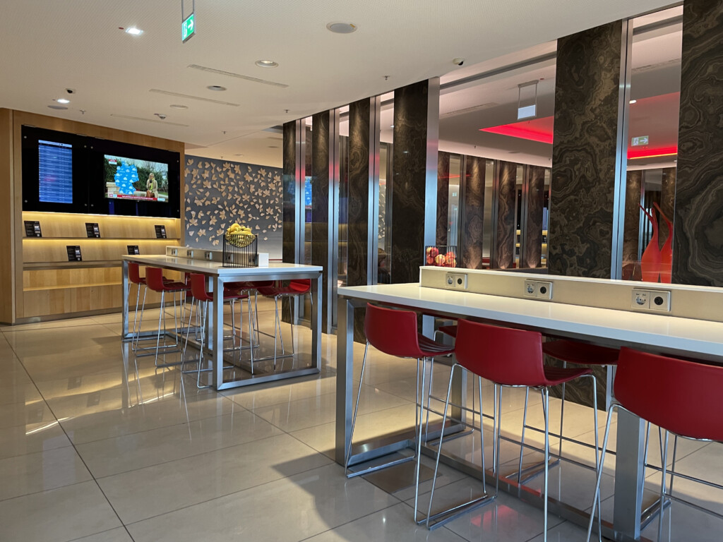 a room with a bar and red chairs