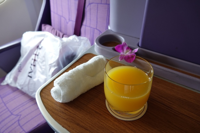 a glass of orange juice and a towel on a table