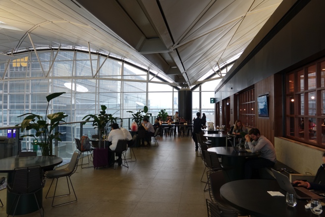 people sitting at tables in a room with large windows