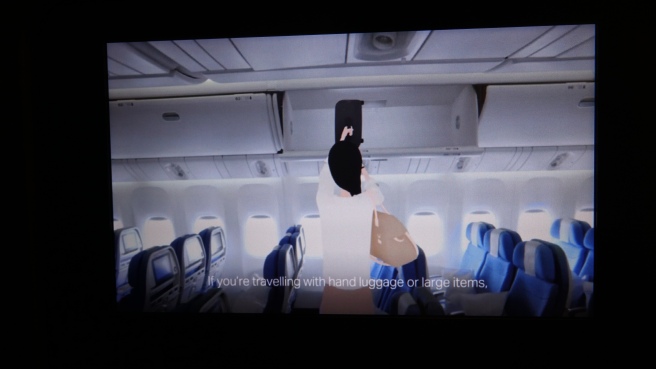 a woman in a white robe holding a luggage bag in an airplane