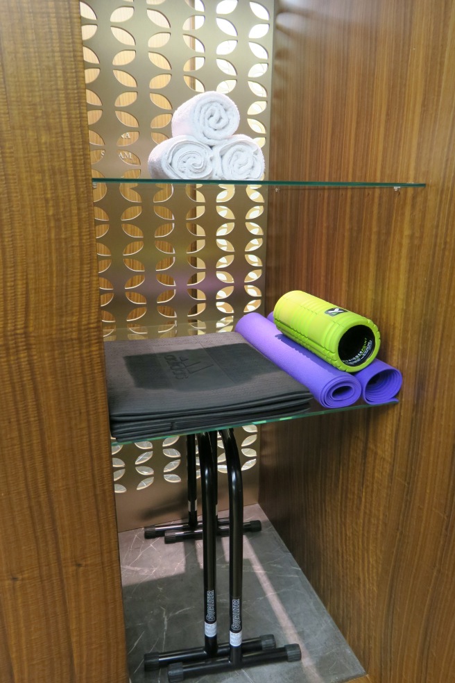 a shelf with rolled yoga mats and towels