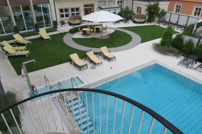 a pool and patio area with chairs and umbrellas