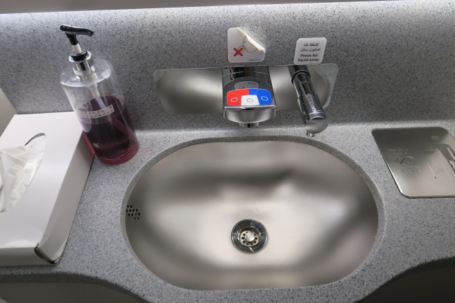 a sink with soap dispenser and a bottle of liquid