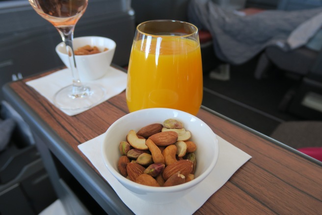 a bowl of nuts and a glass of orange juice