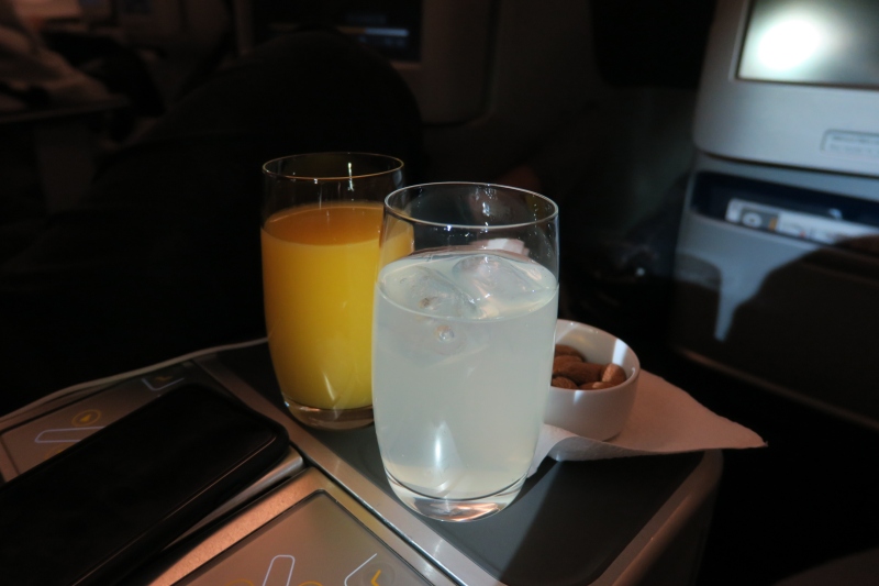 a glass of juice and a bowl of nuts on a tray