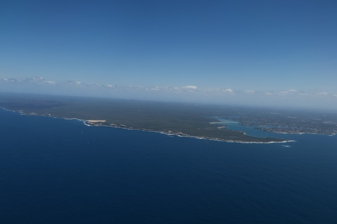 an aerial view of a land with water and blue sky