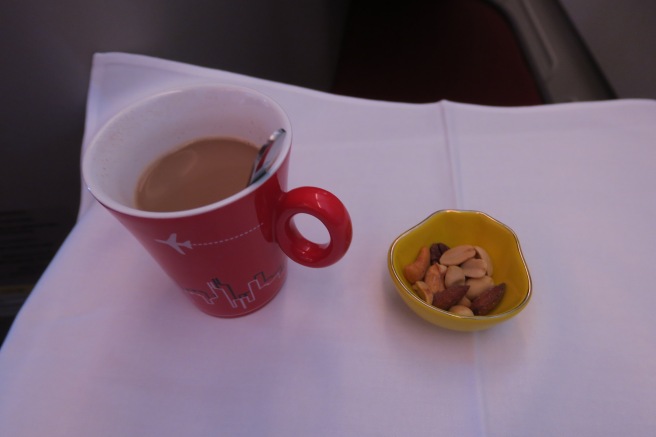 a cup of coffee and a bowl of nuts