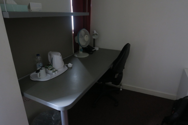 a desk with a fan and coffee cups on it