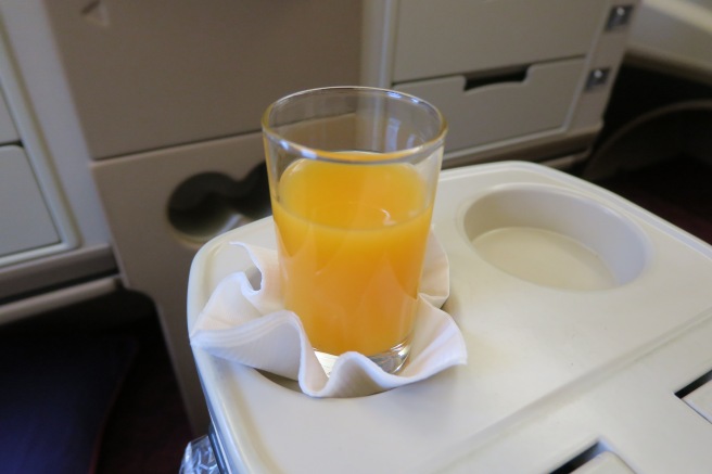 a glass of orange juice on a tray