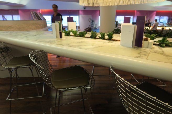 a long counter with chairs and a man in the background