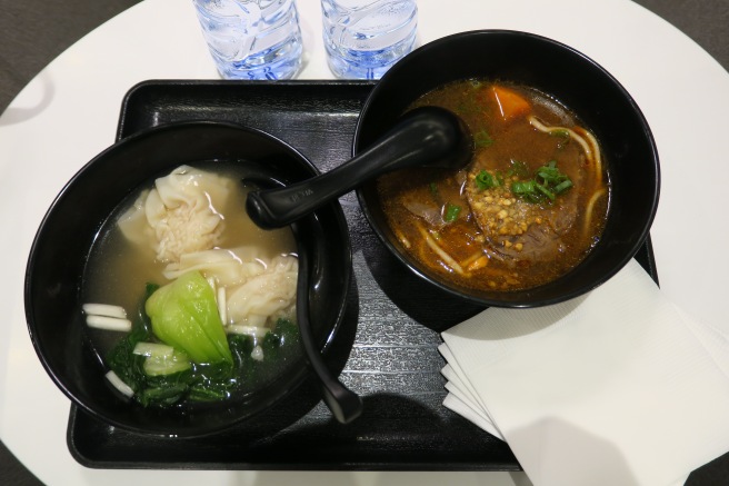 a black tray with bowls of soup and spoons