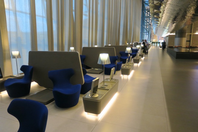 a long room with blue chairs and a couple of people walking