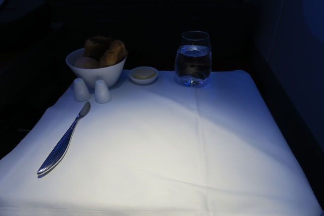 a table with a bowl of bread and a glass of water