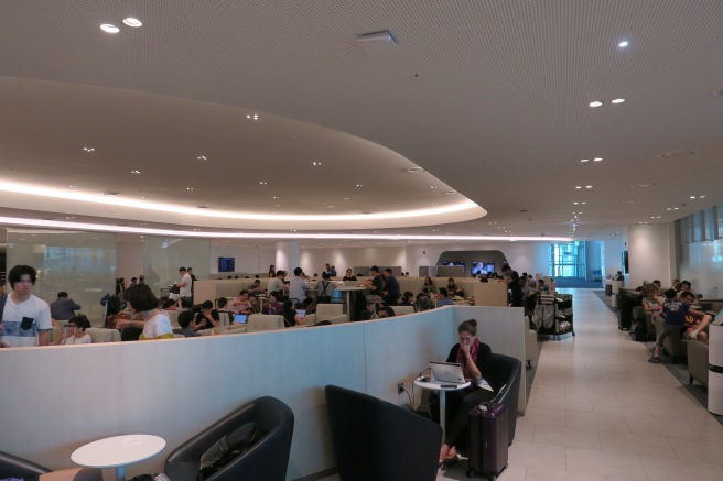 a group of people sitting at tables in a room with a white ceiling