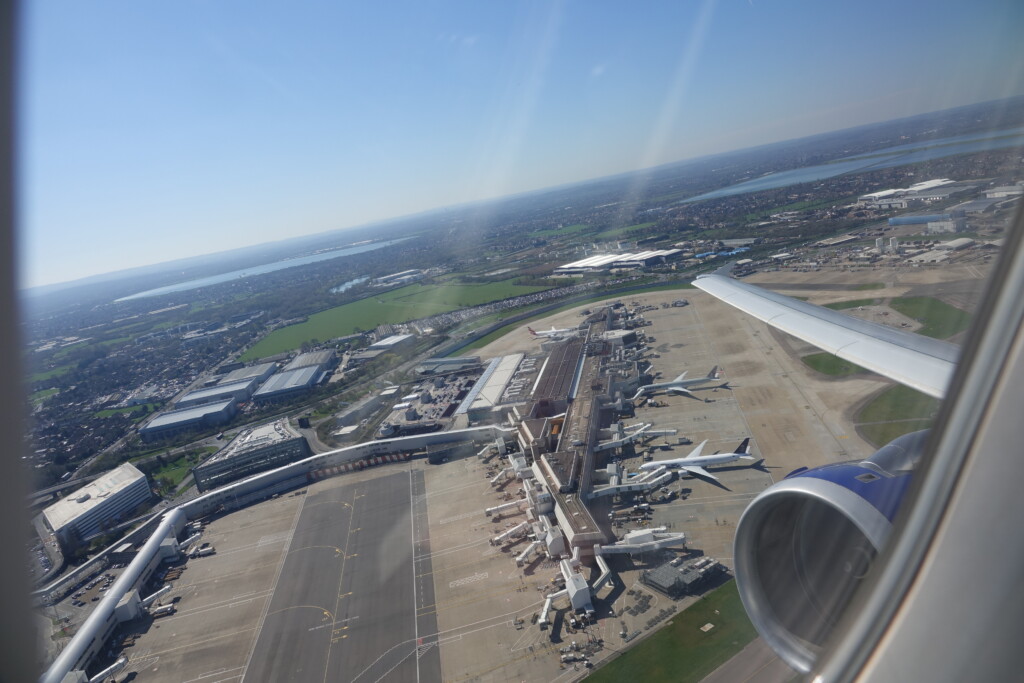 an airplane wing and runway with planes in the background