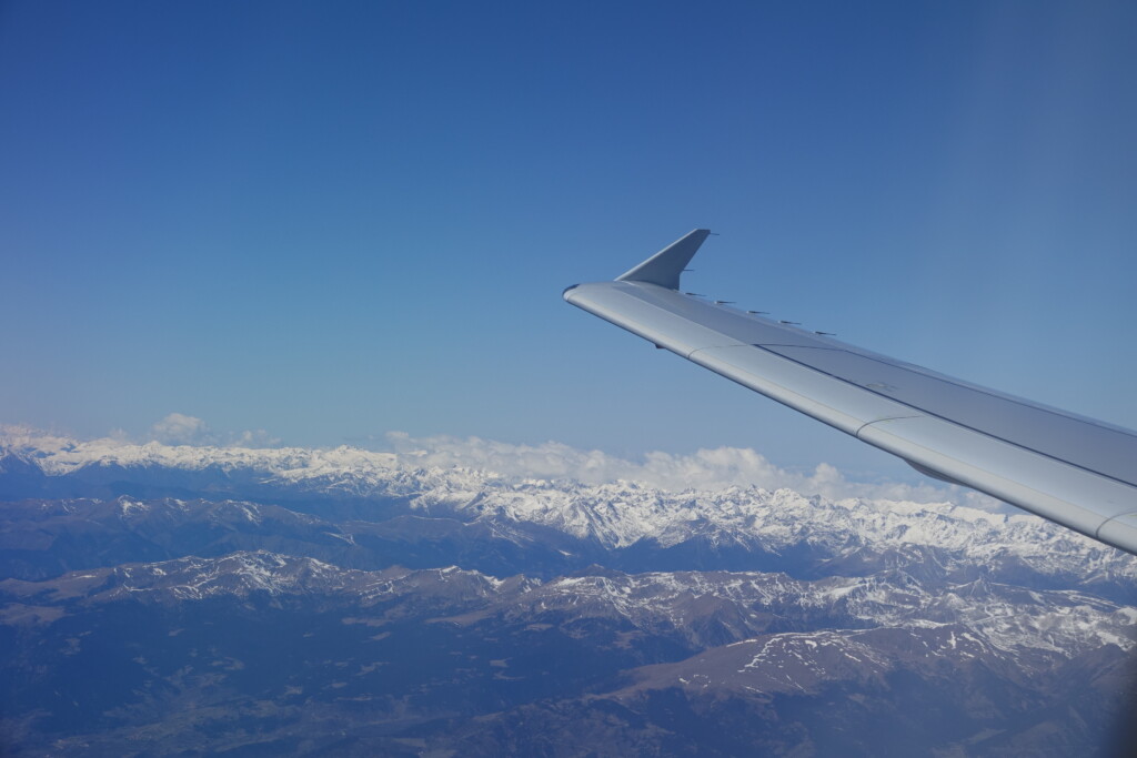 a wing of an airplane above a snowy mountain