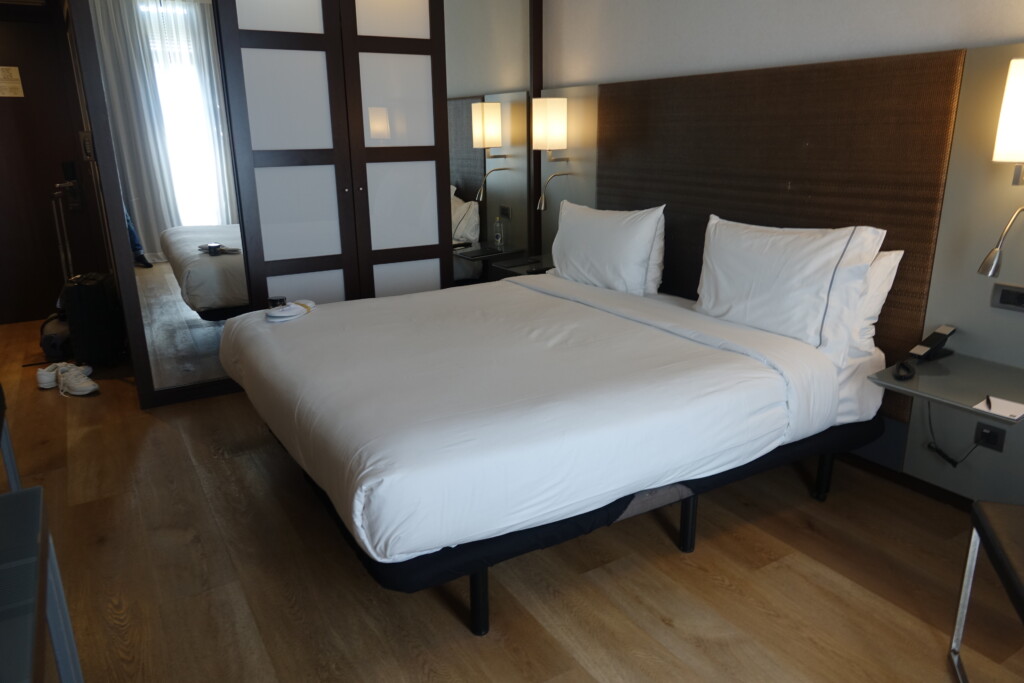 a bed with white sheets and a brown headboard