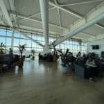 a large room with many people sitting and plants