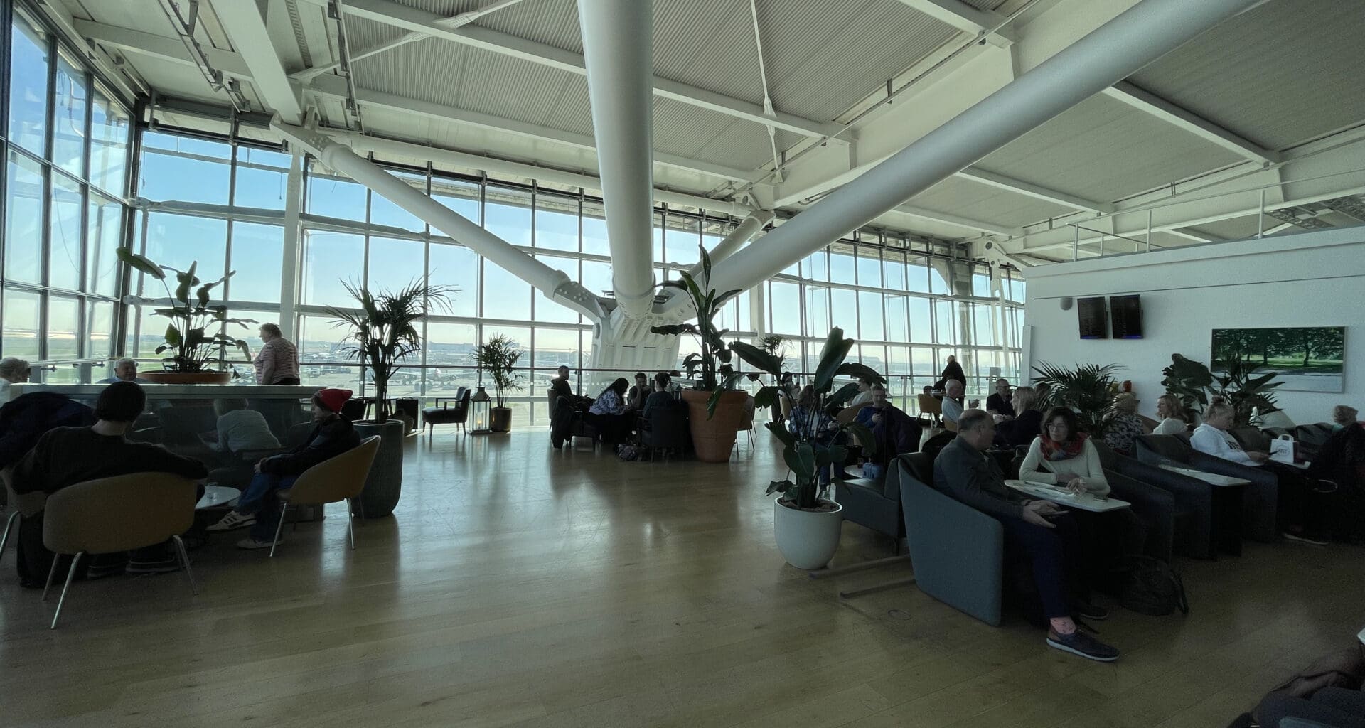a large room with many people sitting and plants
