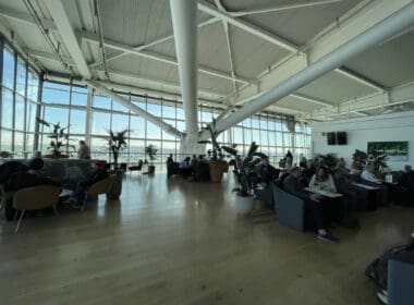 a large room with many people sitting and plants