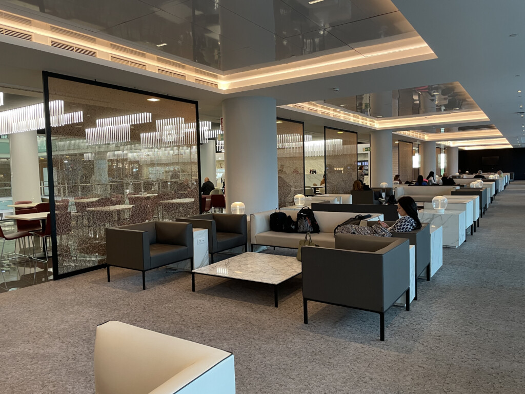 a room with a large glass wall and a group of people sitting on couches