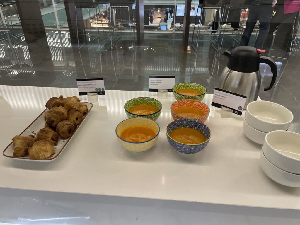 a table with bowls of soup and croissants