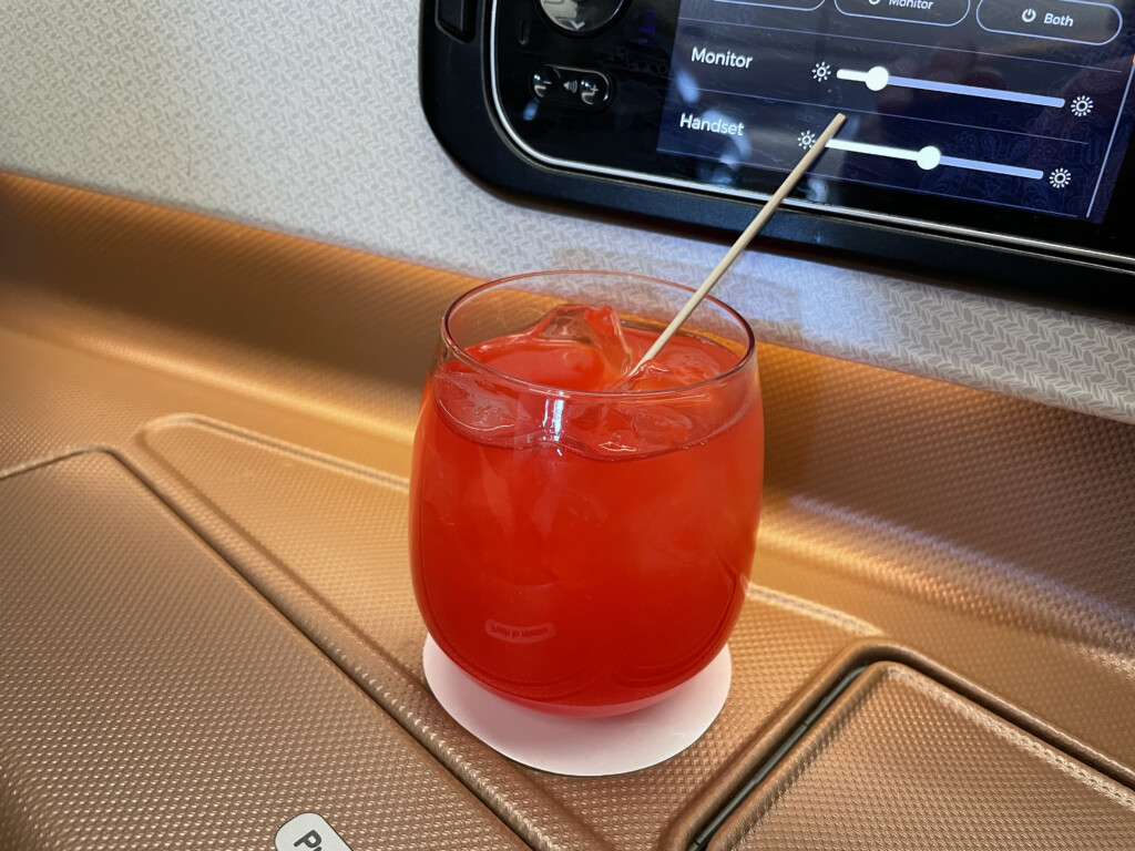 a glass of red liquid with a toothpick in front of a screen