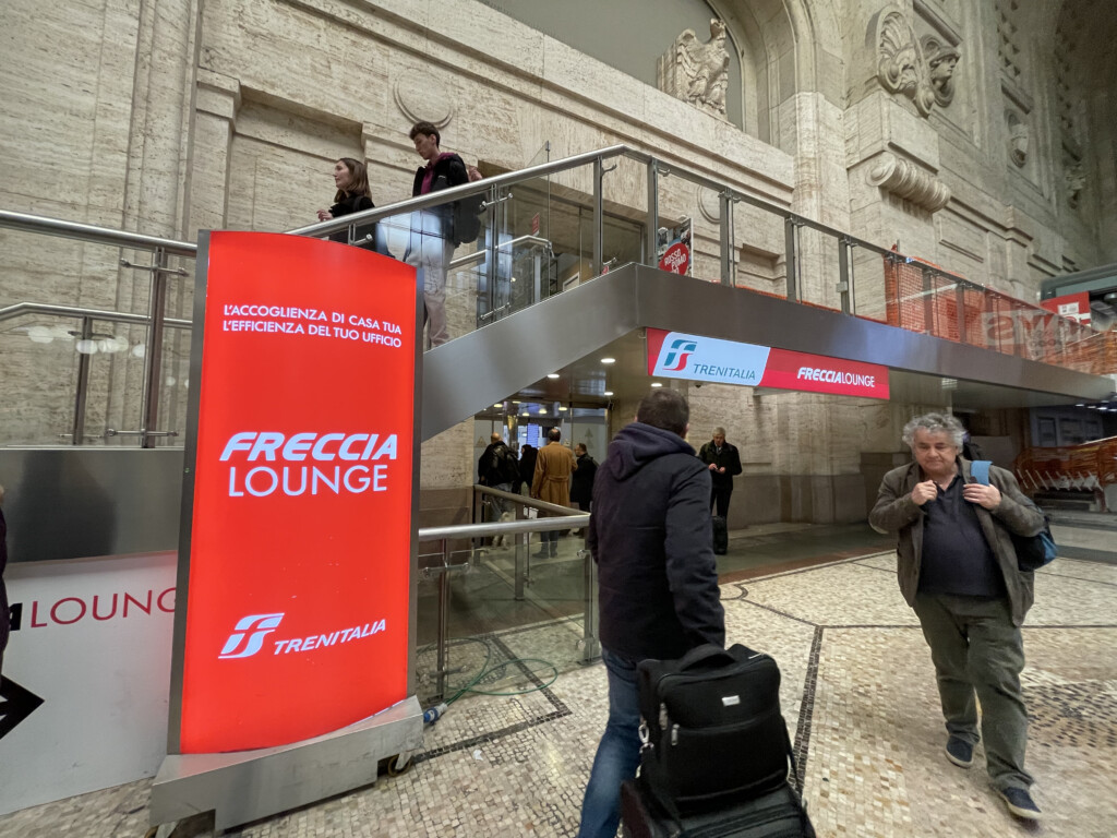 people walking down a staircase with a sign