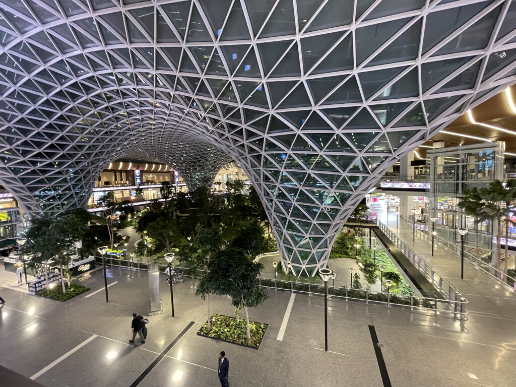 a glass dome structure with trees and people walking around