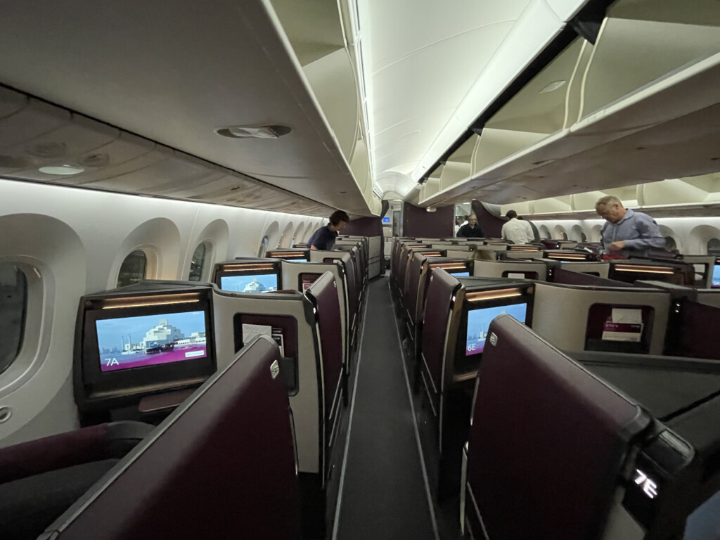 a row of seats with monitors on the side of the plane