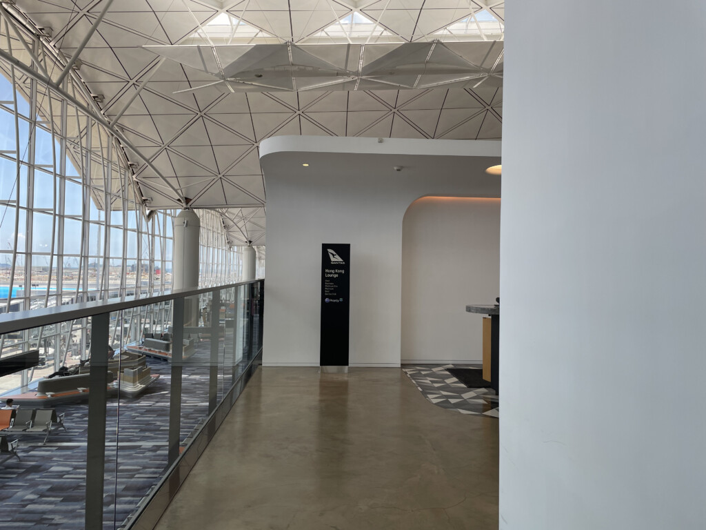 a hallway with a glass wall and a black sign