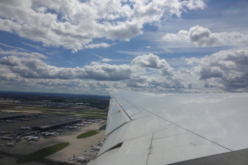 an airplane wing and runway with many planes in the background